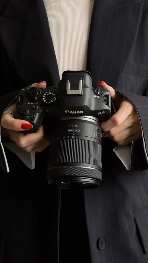 Hands holding a mirrorless camera with a zoom lens