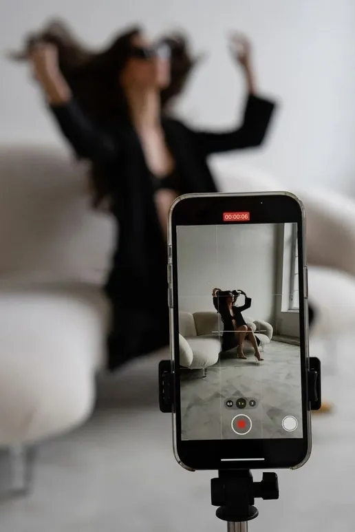 Phone on a tripod recording a woman posing in the background