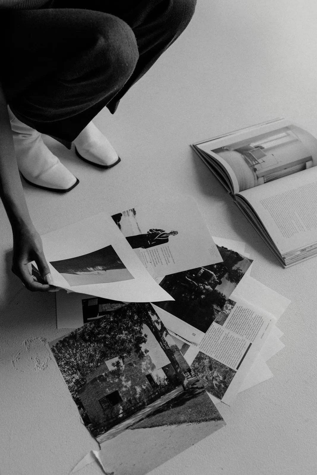 Black and white photo prints and an open magazine spread on the floor